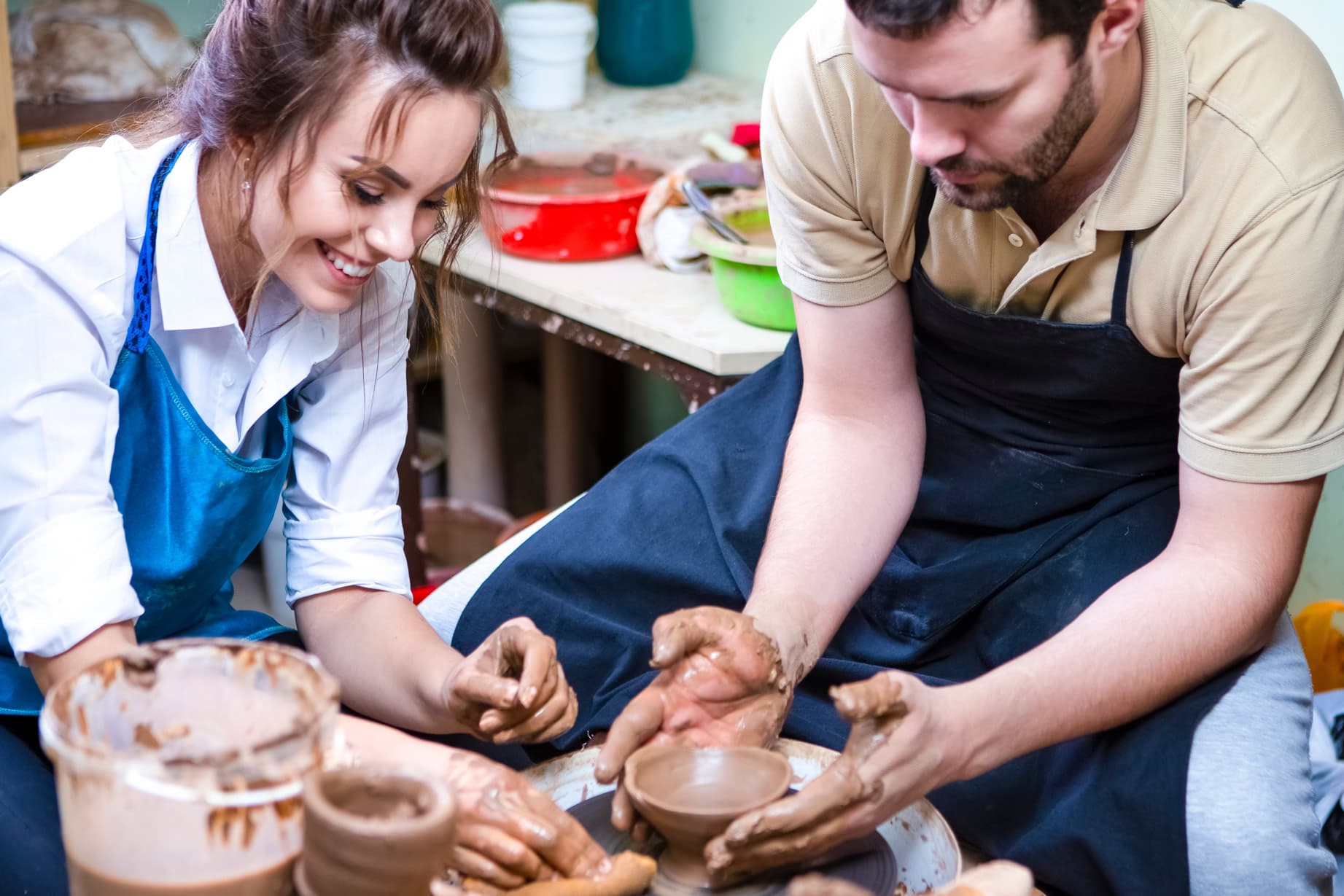 Two people making pottery together in a sunlit workshop studio